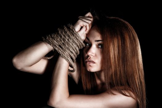 Beautiful young woman with tied arms over black background