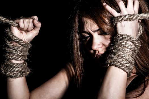 Beautiful young woman with tied arms over black background