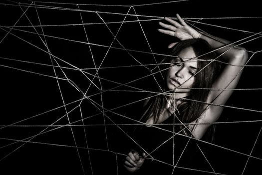 Young woman entangled the net of ropes over black background