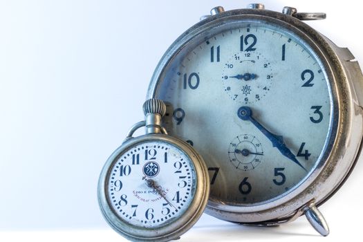 An old rusty alarm-clock with a pocket clock on white background.