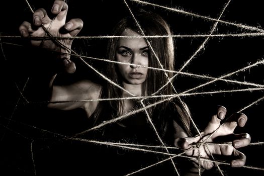 Pale woman snatching the ropes over black background