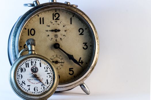 An old rusty alarm-clock with a pocket clock on white background.