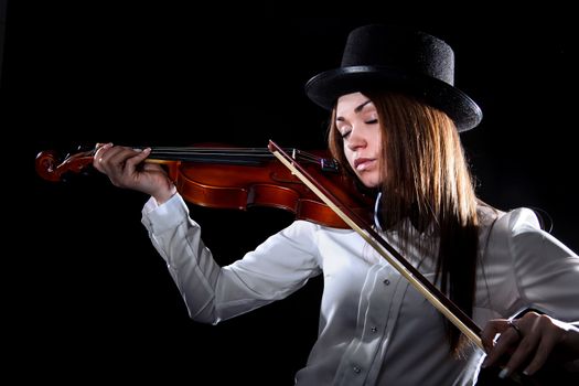 Pretty young woman playing a violin over black background