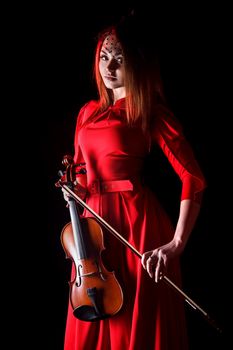 Pretty young woman holding a violin over black background