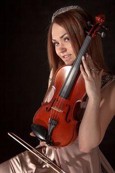 Pretty young woman holding a violin over black background