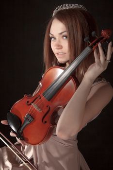 Pretty young woman holding a violin over black background