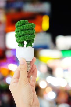 green light bulb and defocused city night light background, green energy concept