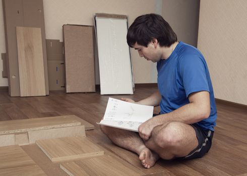 Young man puzzled about assembling flatpack closet