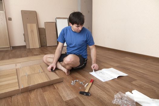 Young man puzzled about assembling flatpack closet