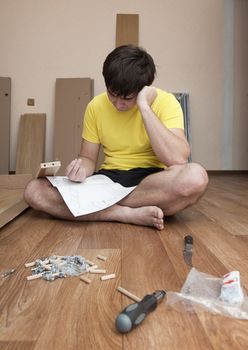 Young man puzzled about assembling flatpack closet