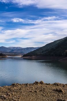 Ladonas artificial lake in Arcadia, Greece against a blue sky with clouds, and mountains as background