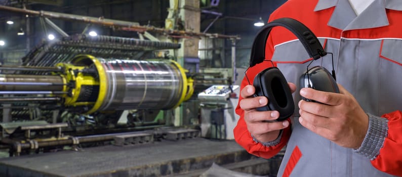 Worker with protective headphone at man hands at industrial factory