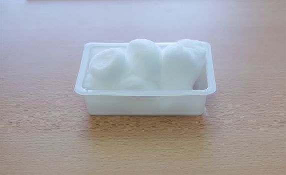 Medical cotton balls for cleansing on white box on table.