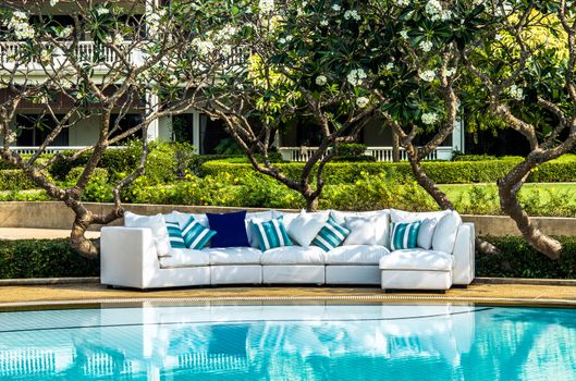 Outdoor furniture with cushions and pillows in the garden by the pool
