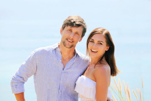 Cheerful couple portrait posing at blue sea background