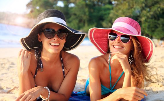 Beautiful young women in sunhats laying on beach