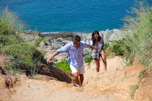 Young couple hiking on the hill near sea