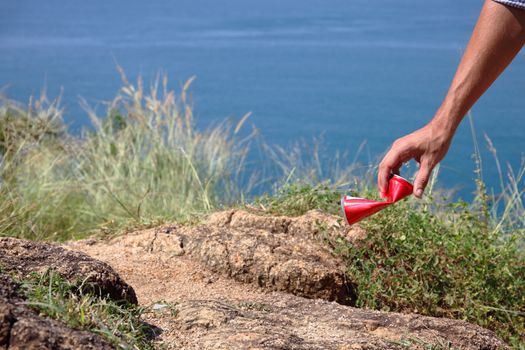 Man picking up litter can on rock at seaside