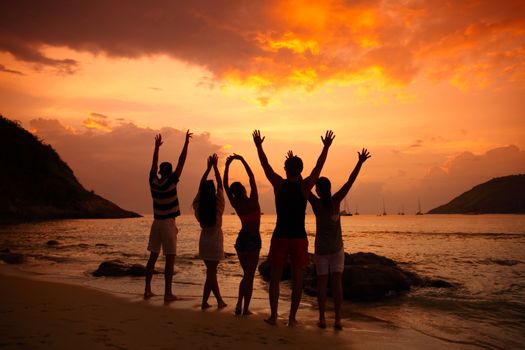 Group of people partying on beach at sunset