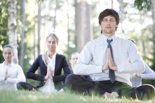 Business people practicing yoga in park