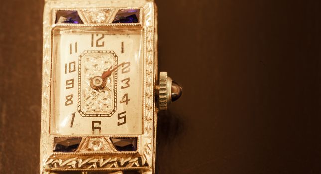 Antique luxury woman’s platinum watch with diamonds and sapphires on a black background