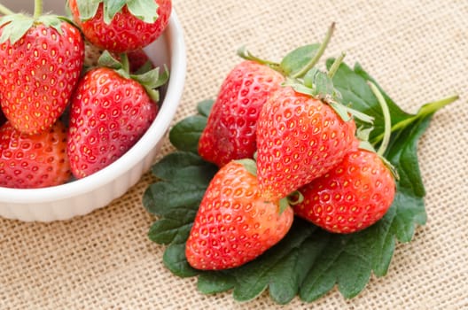 Strawberry with green leaf on sack background.