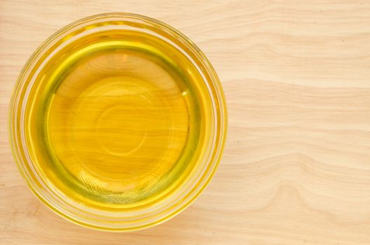 Vegetable oil in glass cup on wooden background.