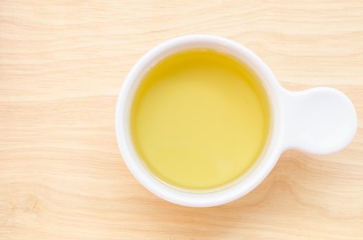 Vegetable cooking oil in a ceramic white bowl on wooden background