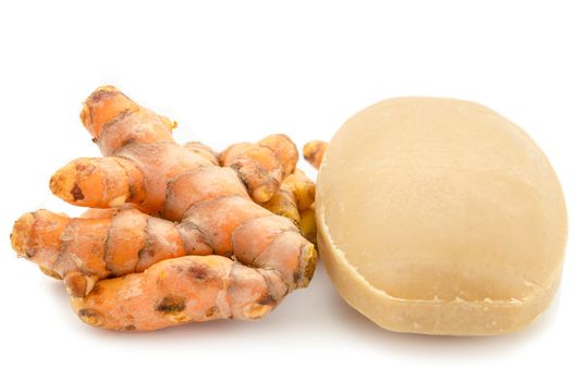Soap made of turmeric with fresh turmeric on white background.