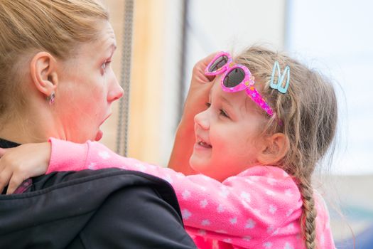 Young mother poses faces and cheers his three-year daughter