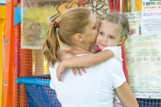 Young mother hugging her daughter, three-year standing soft gaming room