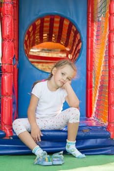 Tired but happy three year old girl sitting on the threshold of a soft game room