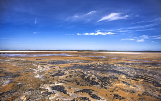 Perfect beach scene of low  tide, interesting rock formations and pristine white sand and bright blue sky