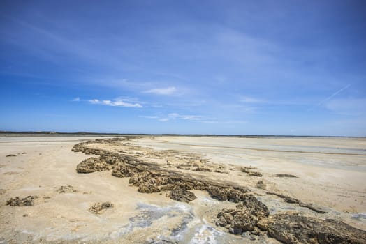 Perfect beach scene of low  tide, interesting rock formations and pristine white sand and bright blue sky