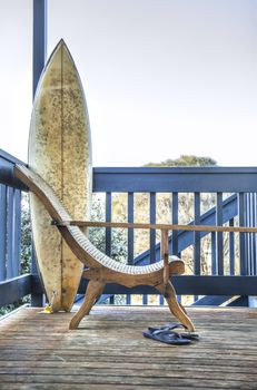 Beautiful wood chair and surfboard on the wooden balcony of a beach house