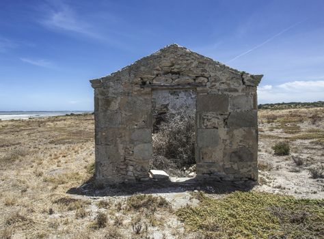 Ruins of a historic house right by the sand of a beautiful beach and wetlands