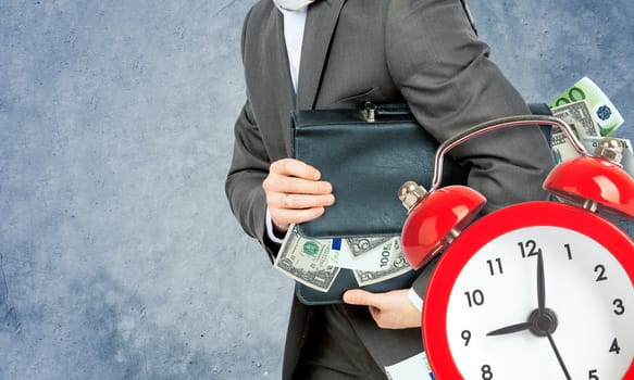 Businessman with suitcase full of money and alarm clock