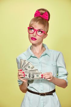 Beauty fashion. Money, banking finance concept. Business woman with dollar bill, cash smiling.Confidence, Pinup hairstyle, pink bow, glasses.Unusual playful, emotion. Shopping happy girl thinking idea