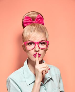 Beauty fashion nerdy woman in stylish glasses thinking, idea. Attractive pretty funny blonde girl smiling. Confidence, success, Pinup hairstyle bow makeup. Unusual playful, expression.Vintage, on pink