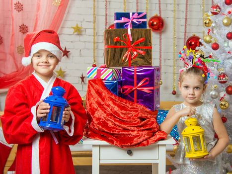 Two girls sisters four and six years in the New Year costumes are at the bag with Christmas gifts