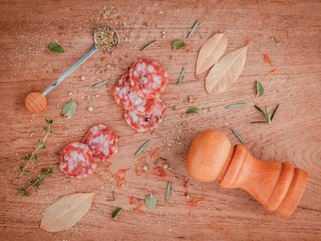 Sliced sausage salami with herbs and spices ,thyme, rosemary, saffron,basil, pepper, and oregano on the teak wood table .