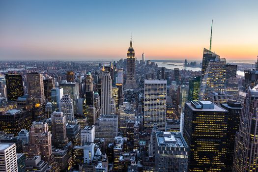 New York City. Manhattan downtown skyline with illuminated Empire State Building and skyscrapers at dusk.