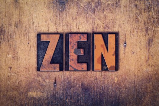 The word "Zen" written in dirty vintage letterpress type on a aged wooden background.