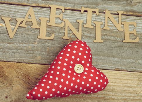 Valentine Theme Background with Cardboard Words and Handmade Textile Red Polka Dot Heart closeup on Rustic Wooden background