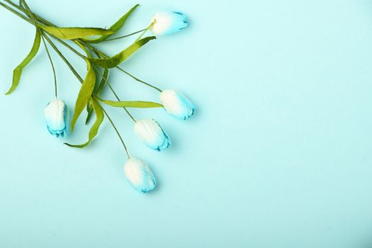 One tiny tulip mulberry paper flowers small bouquet in corner on tender blue background