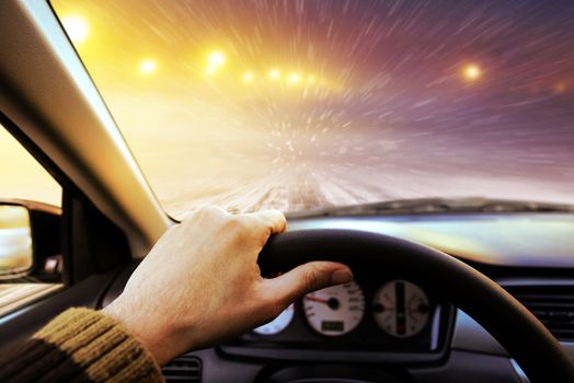 Driving on snow covered winter road with shining streetlights at night