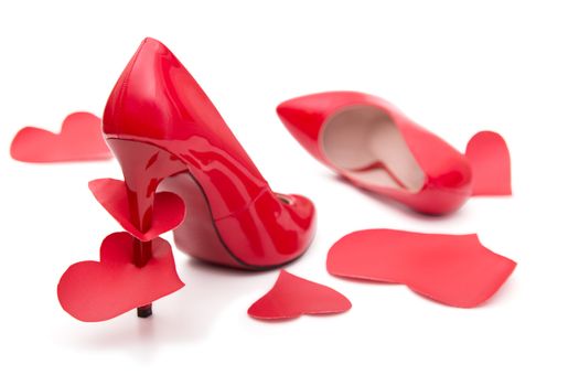 Red shoes with a high heel and stomped and strung on a hairpin of the heart on a white background