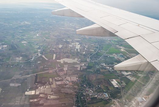 aerial view of the landscape when viewed from the window over the wing of airplane.
