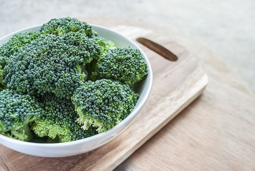 Fresh broccoli vegetable in white bowl on wooden table