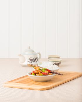 Bowl of Chinese cashew chicken served with white rice and tea.